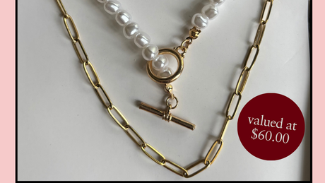 Necklace stack with pearl and paperclip chain on a white background, offered free with every order over $180.