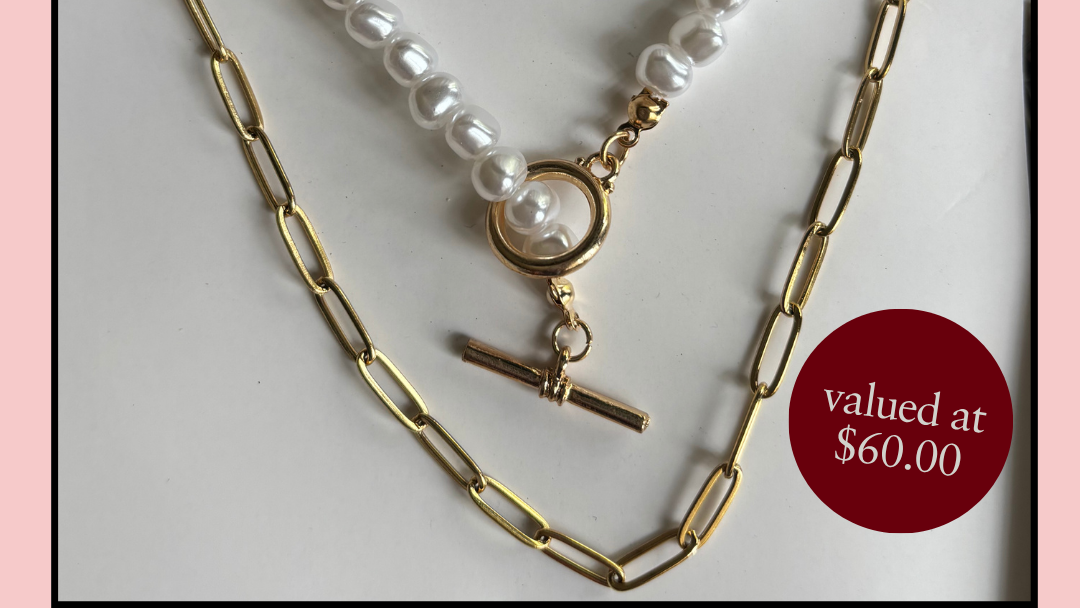 Necklace stack with pearl and paperclip chain on a white background, offered free with every order over $180.