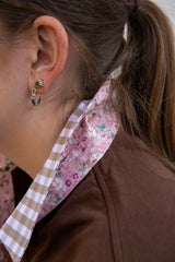 Close-up of a woman wearing a chocolate brown rugby with gingham and floral trim on collar 