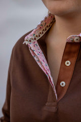 Close-up of a chocolate brown rugby shirt with a floral collar and buttons.